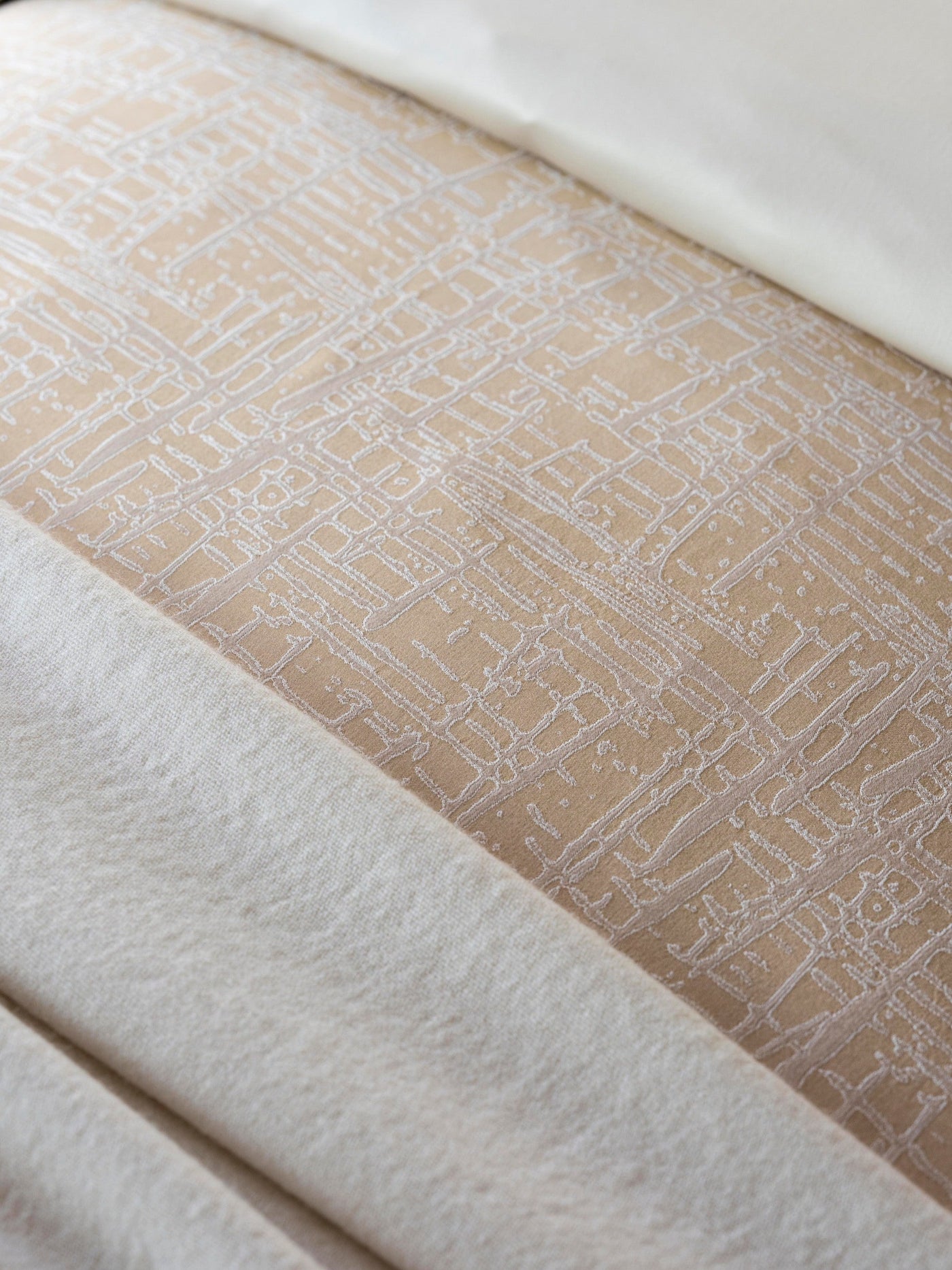 Close-up of Celso de Lemos Partition pillowcase hem, champagne jacquard grid pattern detail.