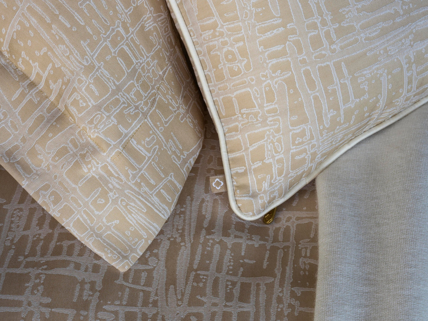 Close-up of Celso de Lemos Partition pillowcases in champagne with tonal map-print pattern.