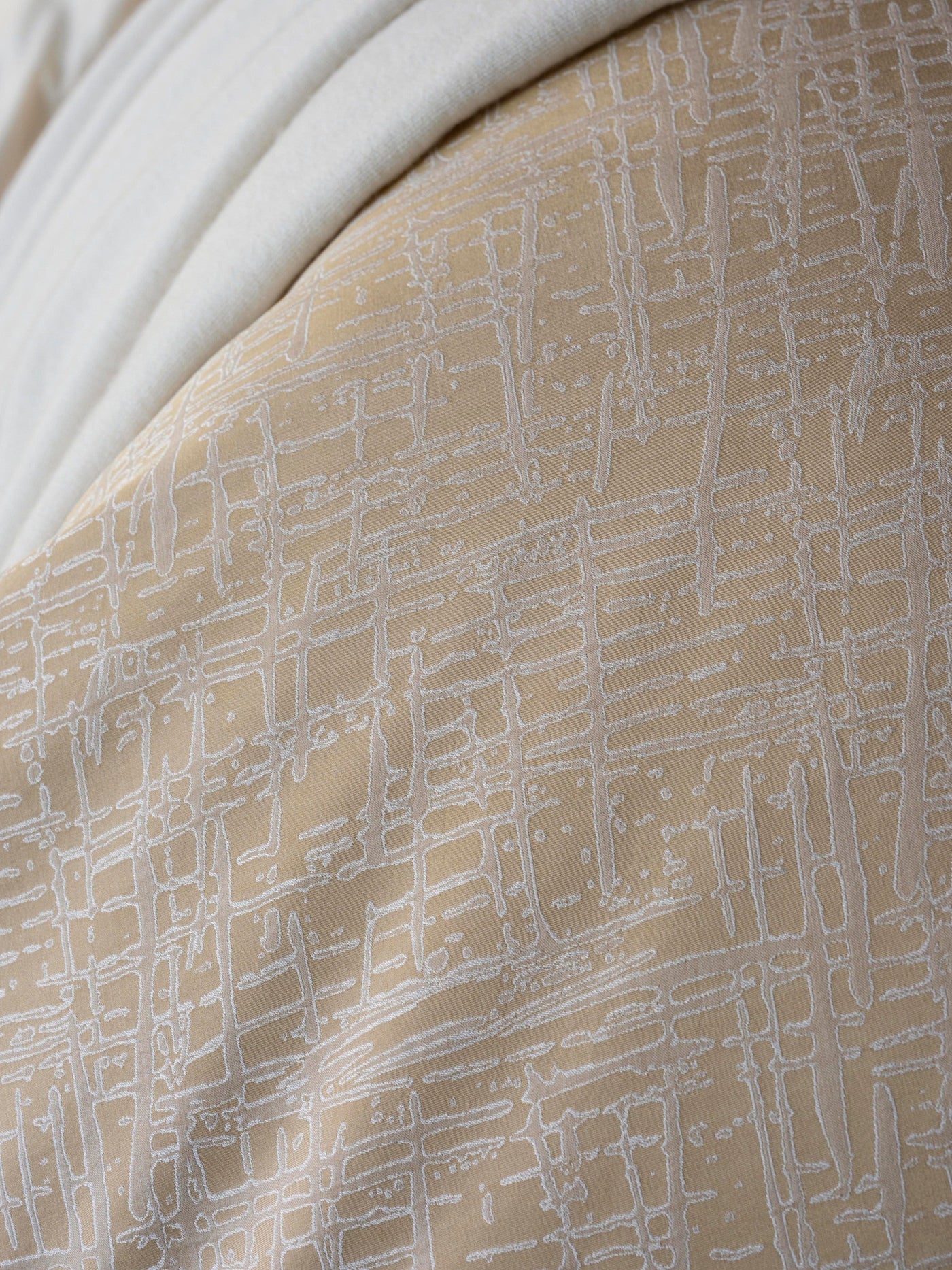 Close-up of Celso de Lemos Partition pillowcase in champagne with woven grid pattern detail.