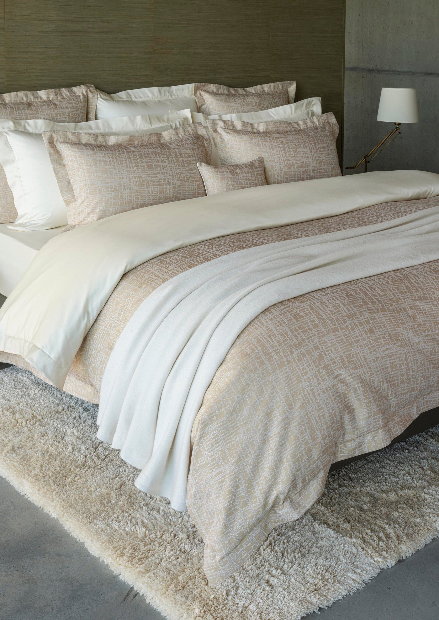 Blush and ivory woven pillowcase styled on a layered bed with textured duvet.