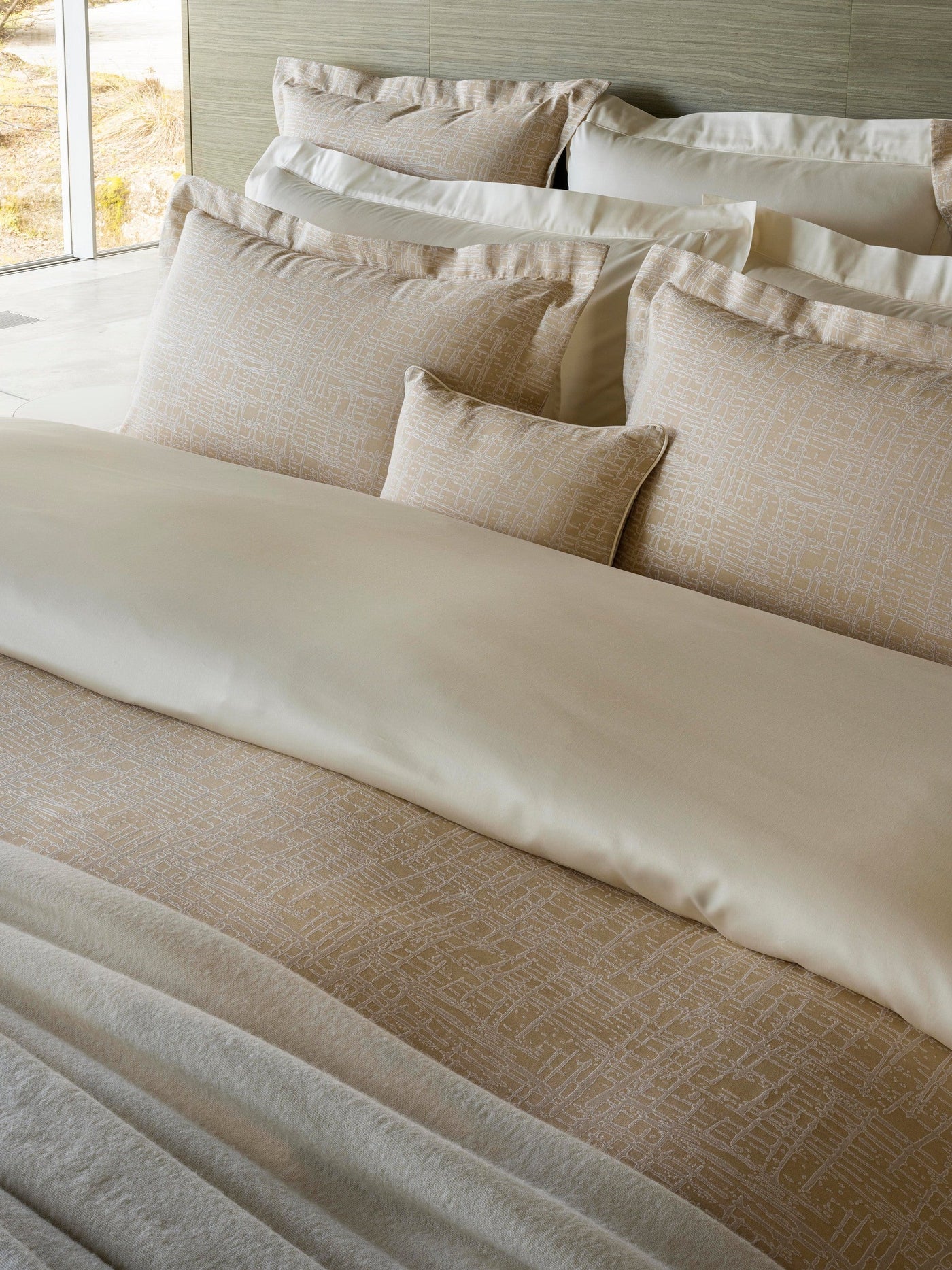 Close-up of champagne textured pillowcase with ivory border, styled on a layered bed.