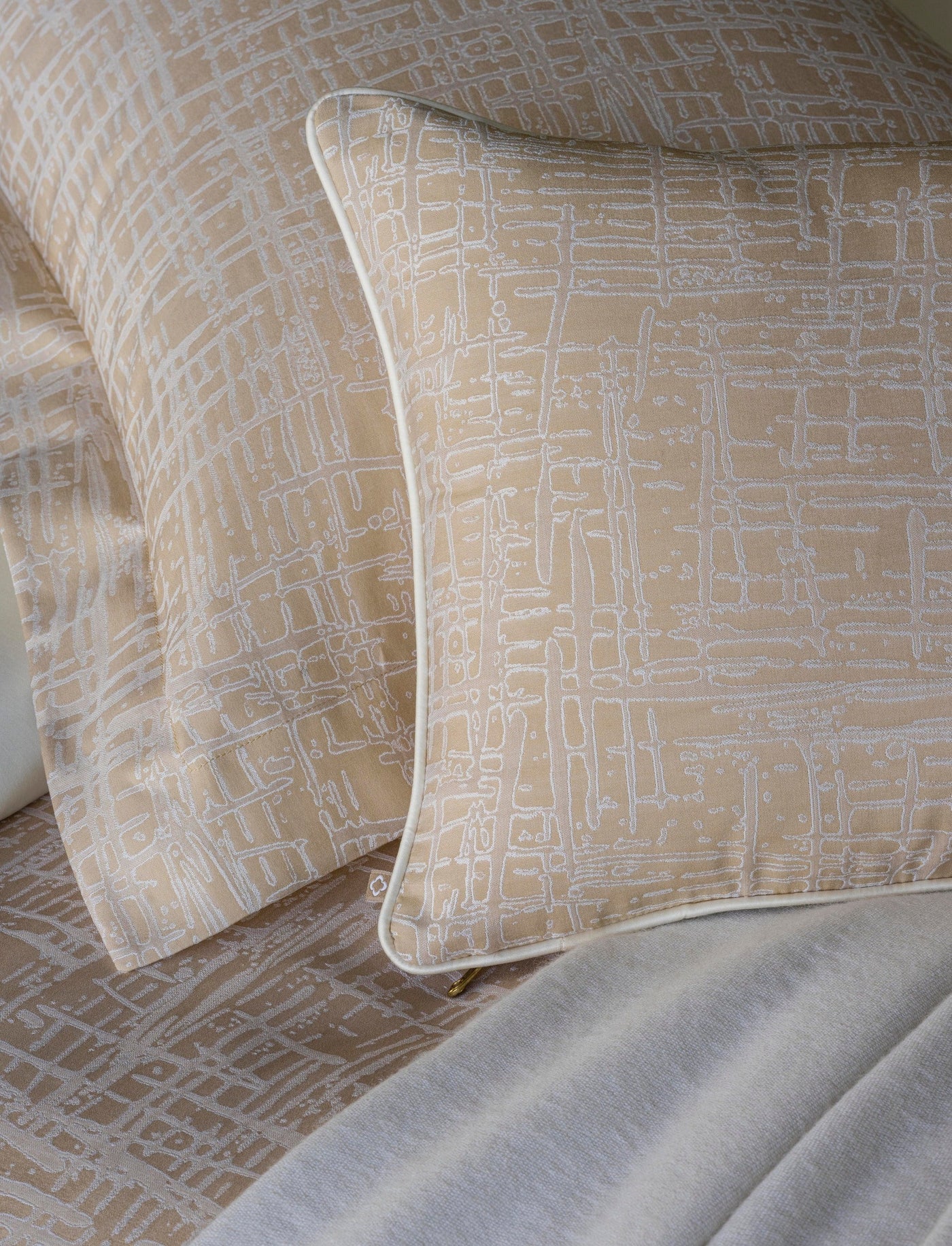 Close-up of Celso de Lemos Partition pillowcase in champagne with ivory abstract line pattern.