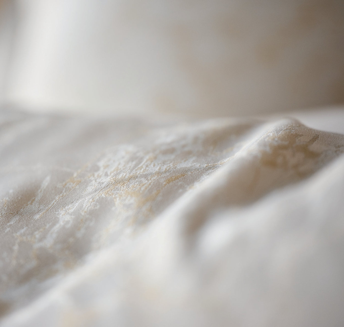 Close-up of ivory Celso de Lemos Parus duvet cover showing delicate embroidered texture.