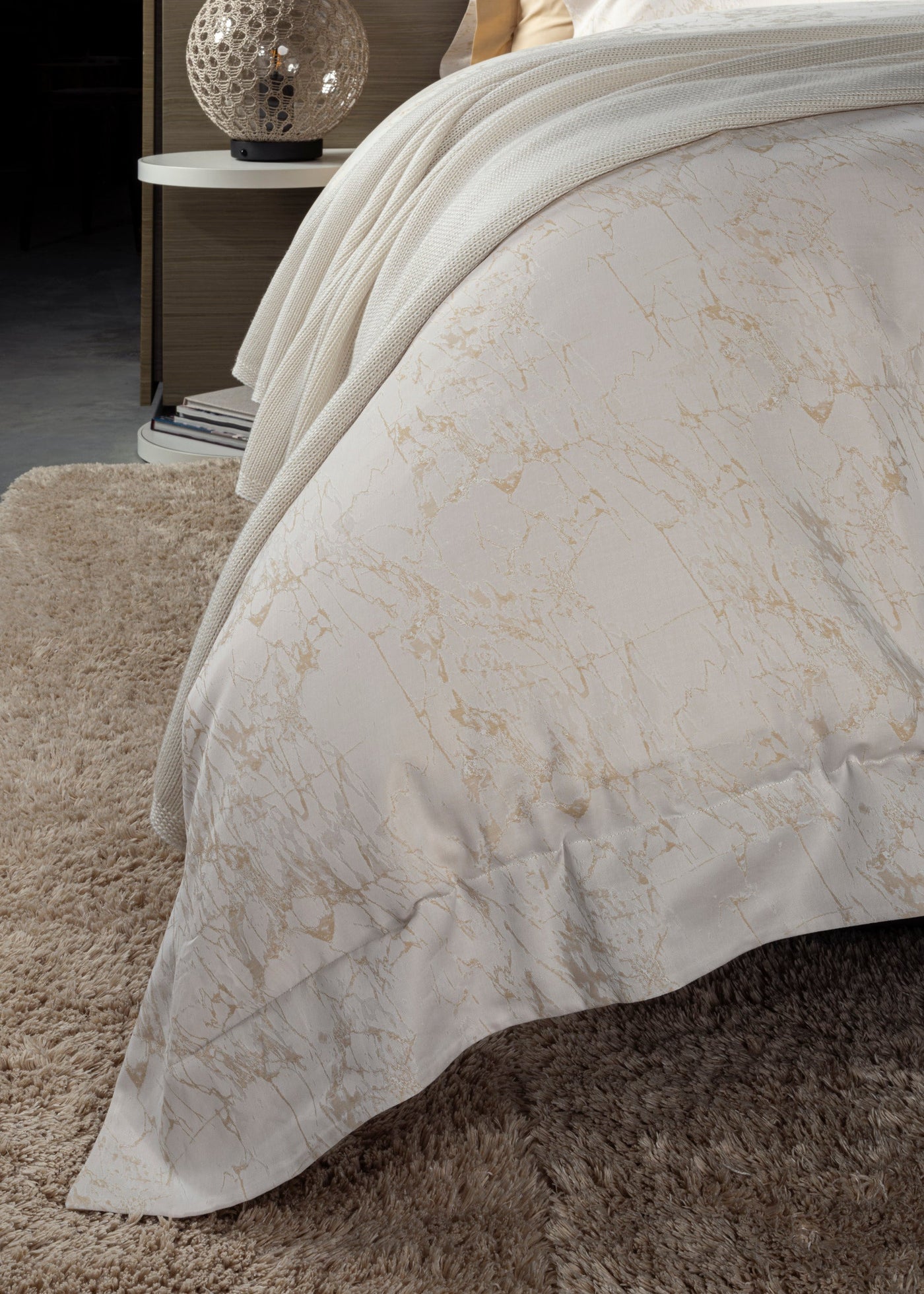 Close-up of Celso de Lemos Parus duvet in ivory with gold marble print, draped over bed.