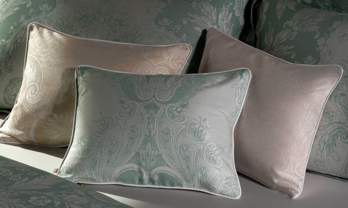 Sage and champagne damask pillowcases with ornate scrollwork, styled on a bed.