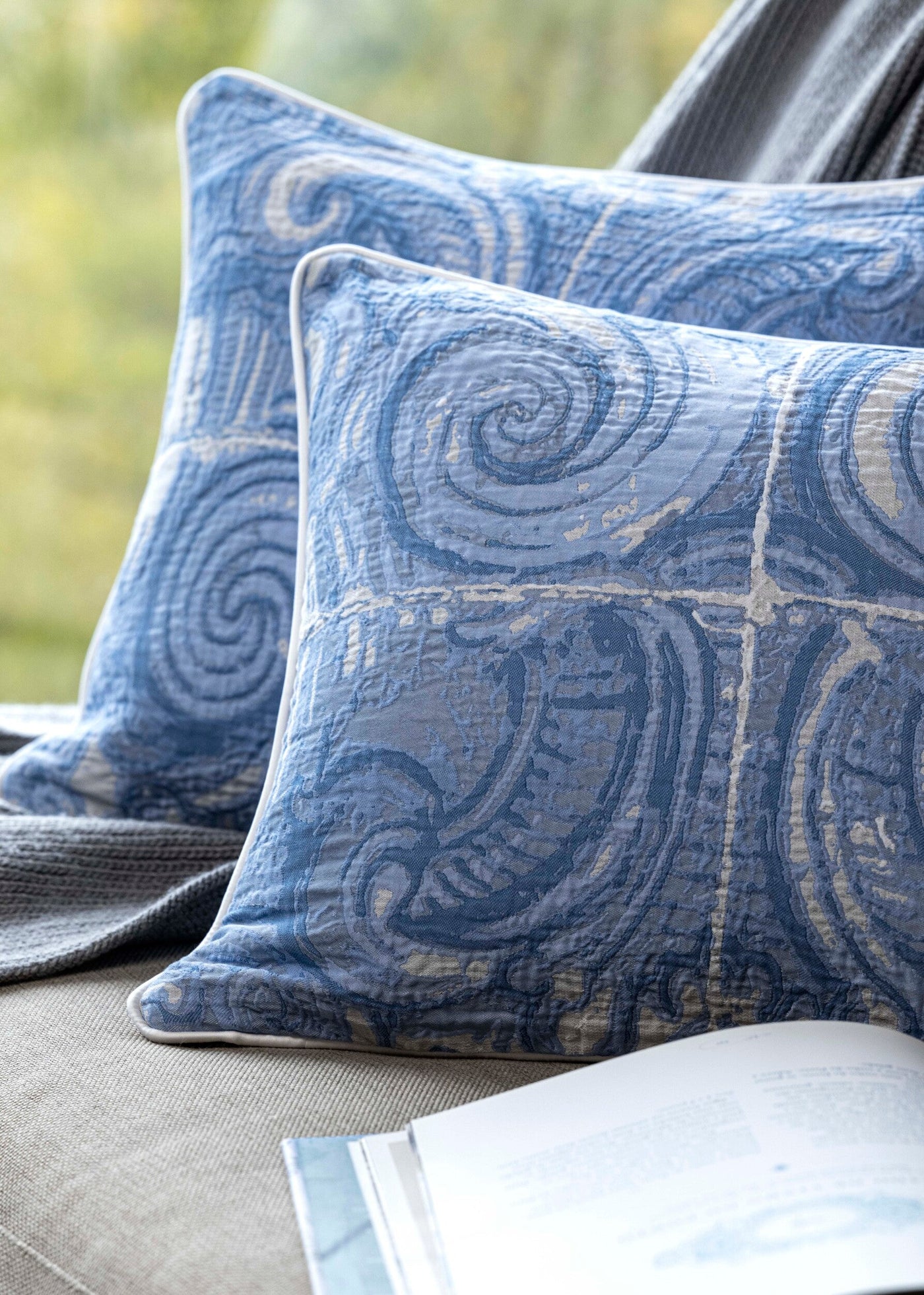 Celso de Lemos Porto pillow covers styled on a bench, showing blue swirl jacquard pattern detail.