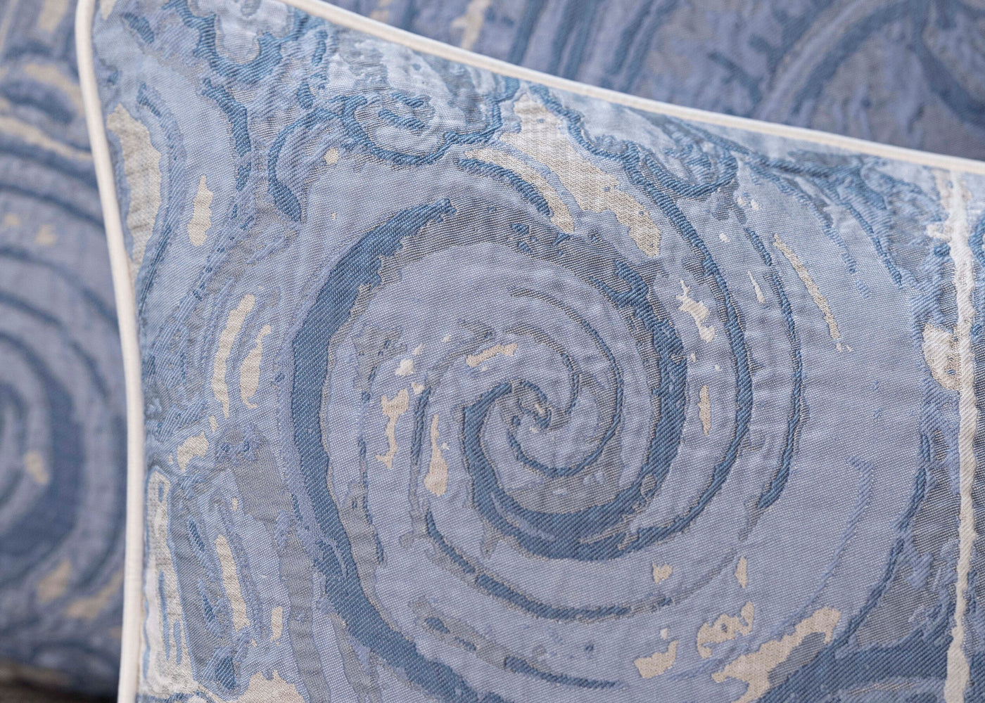 Close-up of Celso de Lemos Porto pillow cover showing swirling blue jacquard pattern with white piping.