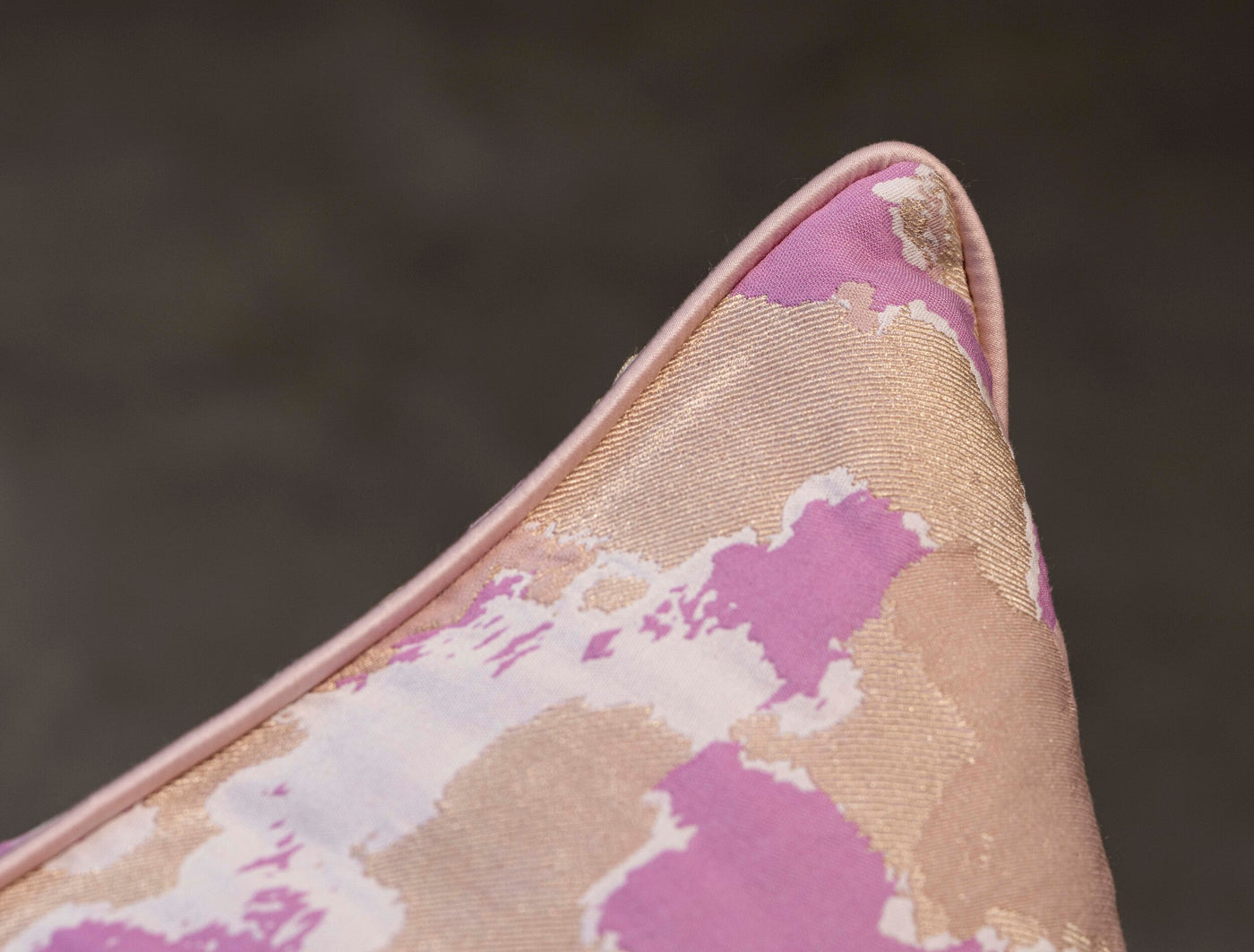 Corner detail of Rosa pillow cover showing pink piping and abstract floral jacquard weave.