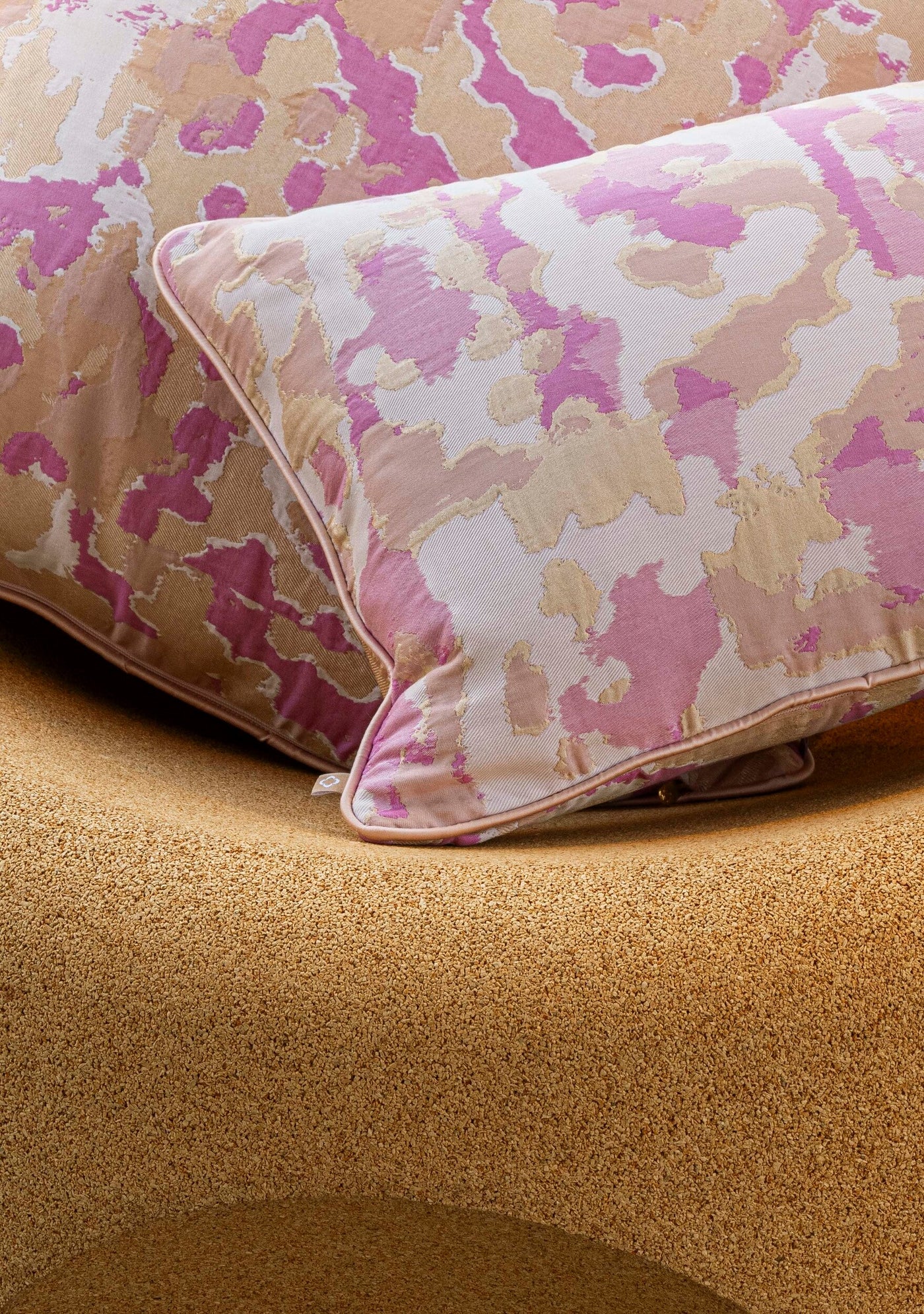 Close-up of Celso de Lemos Rosa pillow cover in magenta and champagne abstract jacquard pattern.