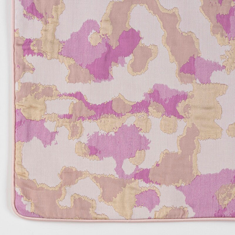 Close-up corner of Celso de Lemos Rosa pillow sham with magenta and gold abstract watercolor print.