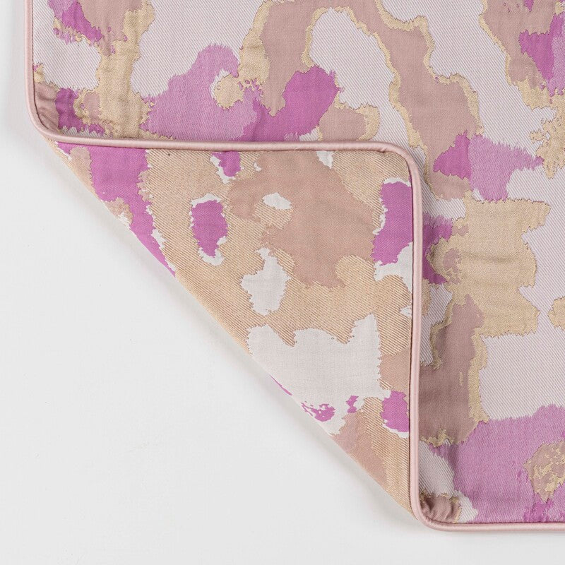 Corner detail of Rosa pillow sham showing pink and gold abstract watercolor print with blush piping.