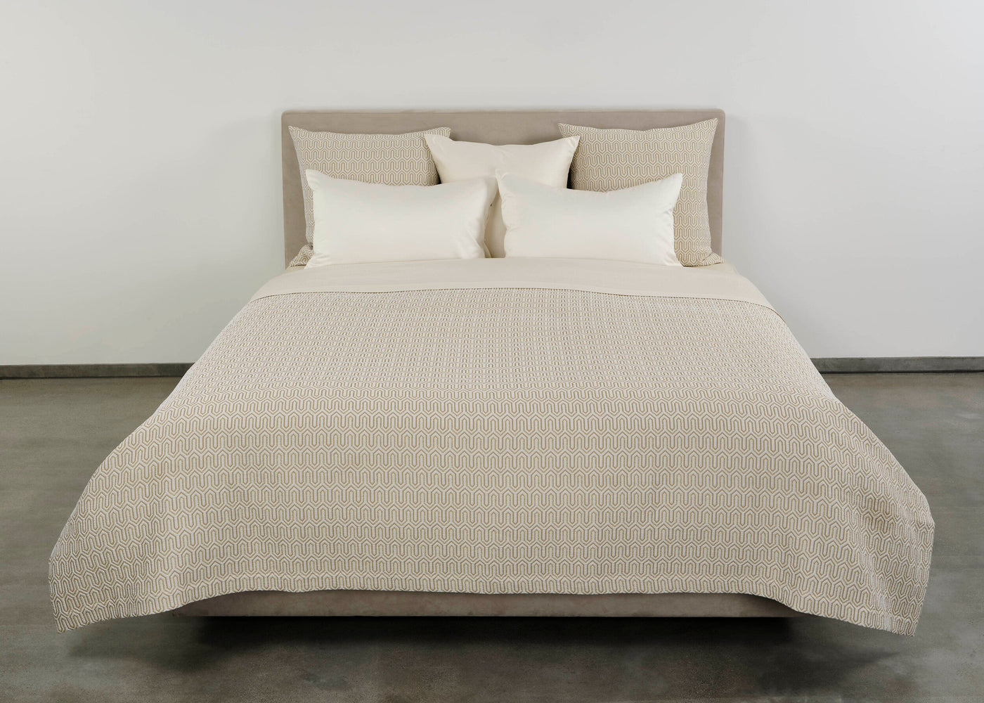 Vendome pillow shams styled on a bed with a neutral quilted coverlet and white pillows.