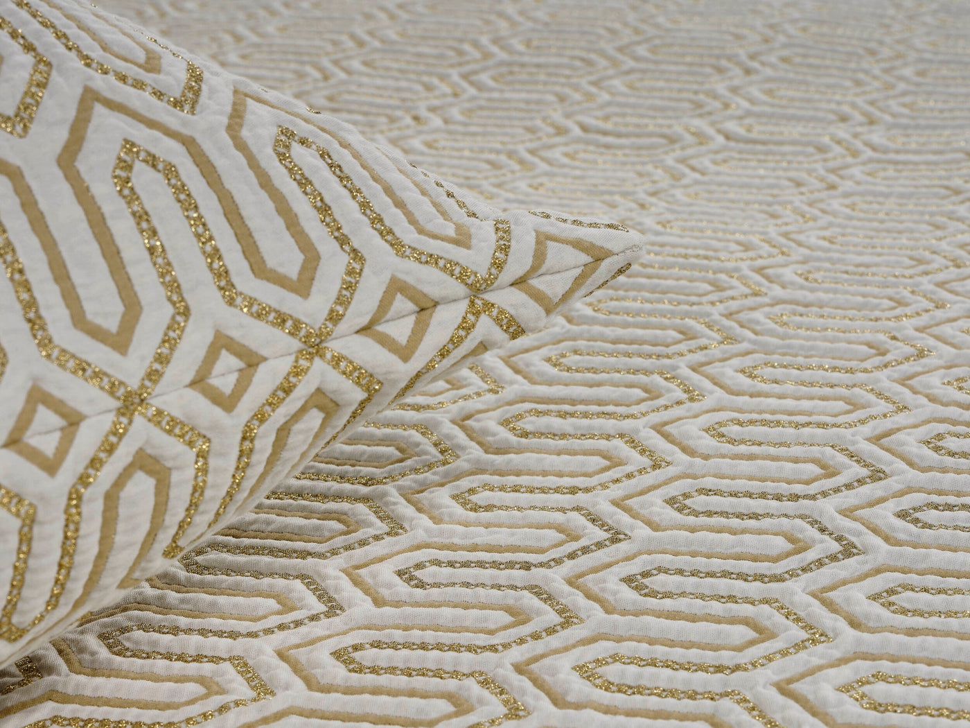 Close-up of Celso de Lemos Vendome pillow cover folded, showing ivory and gold geometric jacquard weave.