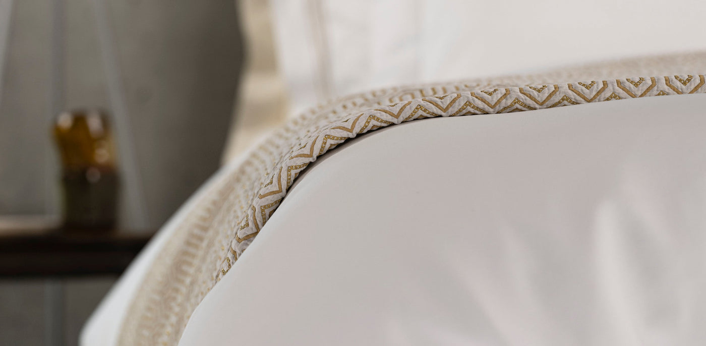 Close-up of Vendome pillow sham's woven champagne trim detail against white linen.