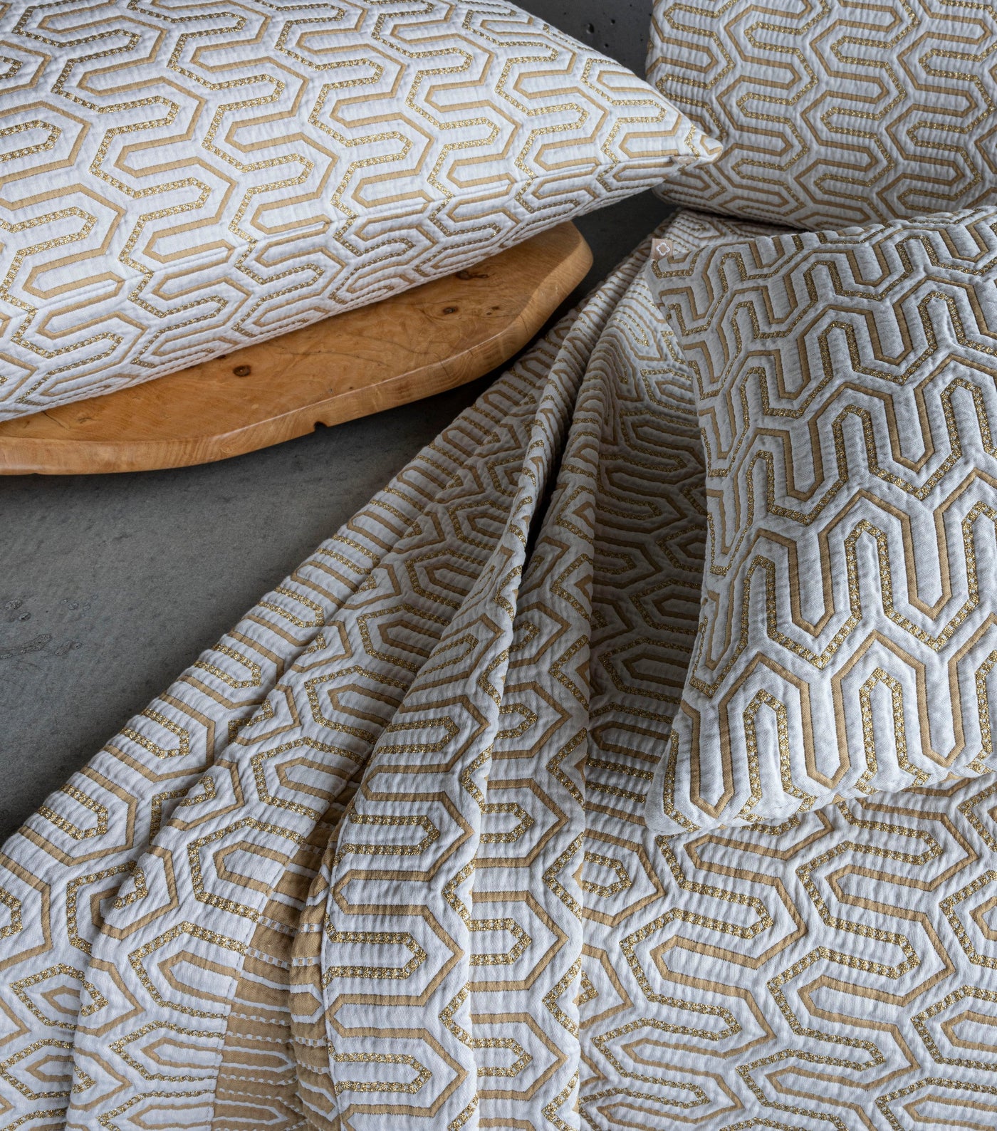 Draped Vendome fabric and pillow covers showing gold geometric hexagon pattern on ivory ground.