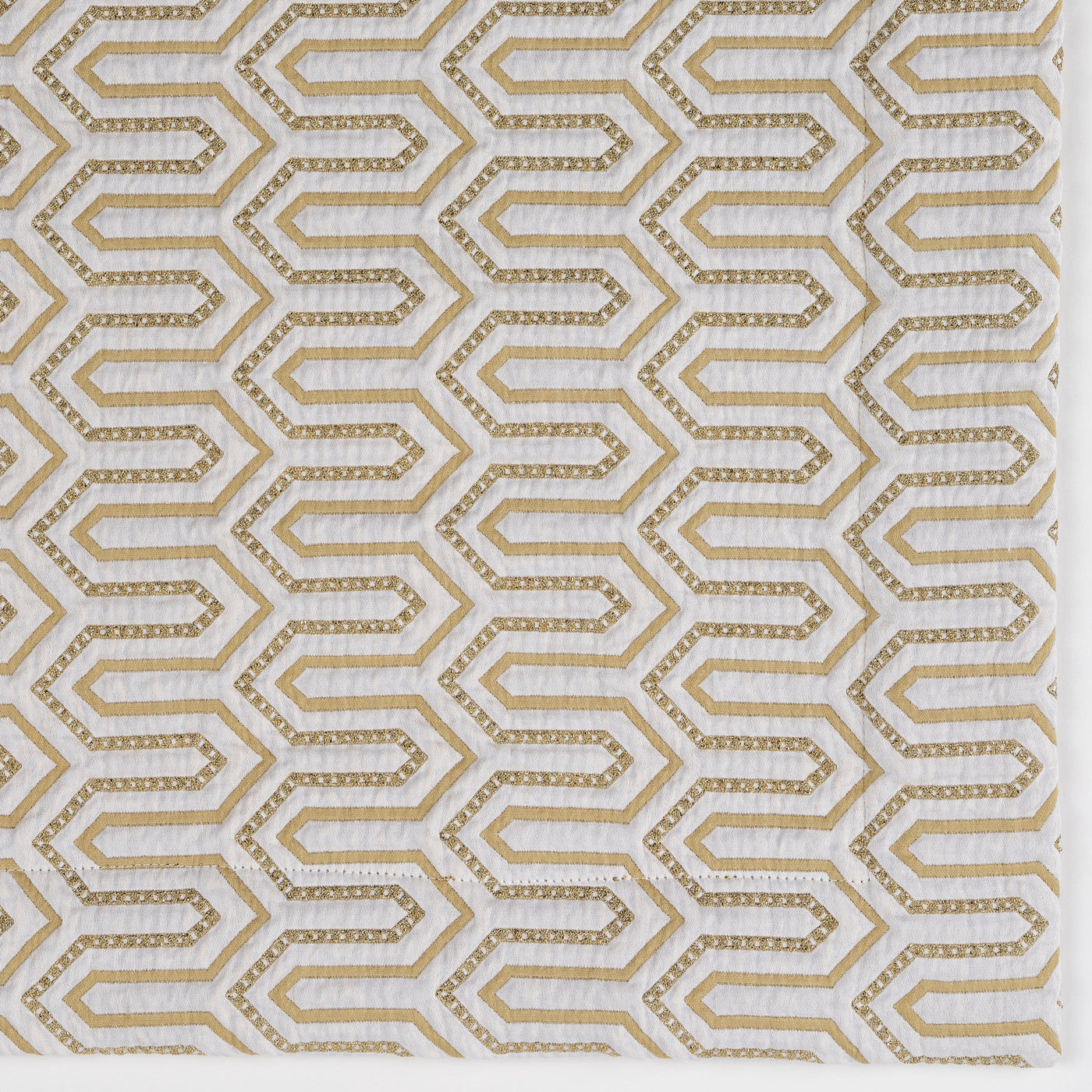 Close-up of Vendome pillow cover fabric in gold geometric hexagon pattern on white.