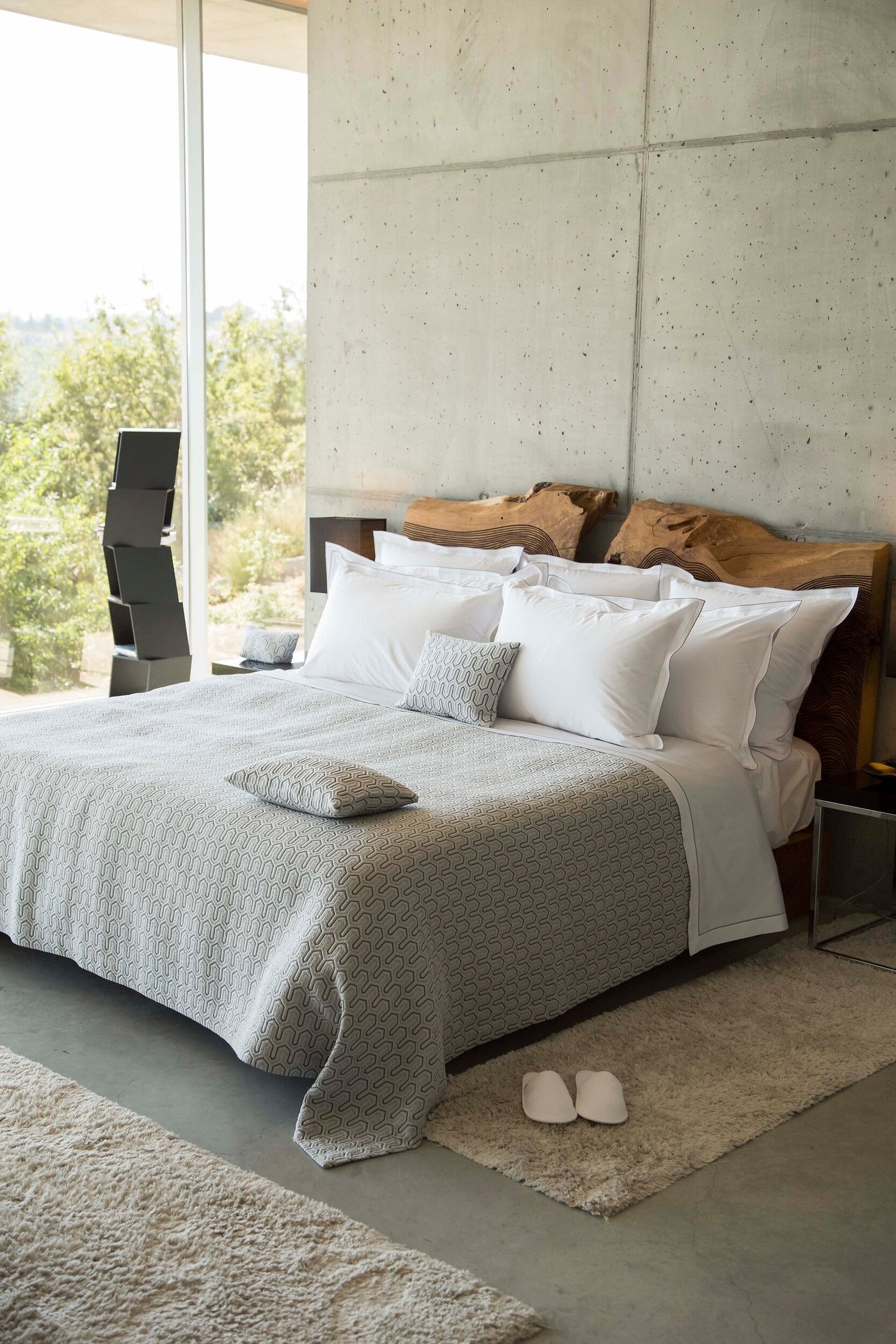 Vendome pillow cover styled on bed with grey patterned coverlet and white Euro shams.