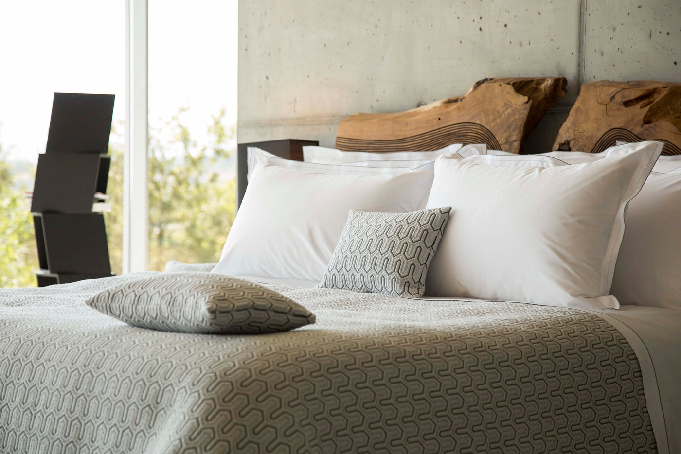Vendome pillow cover styled on a made bed with white pillows and a neutral quilted coverlet.
