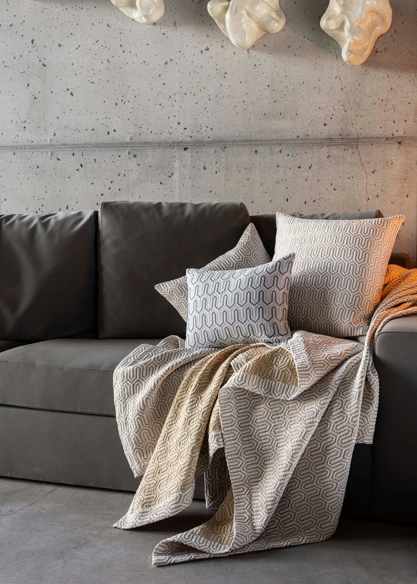 Vendome pillow cover styled on a dark sofa with geometric-patterned throw and cushions.