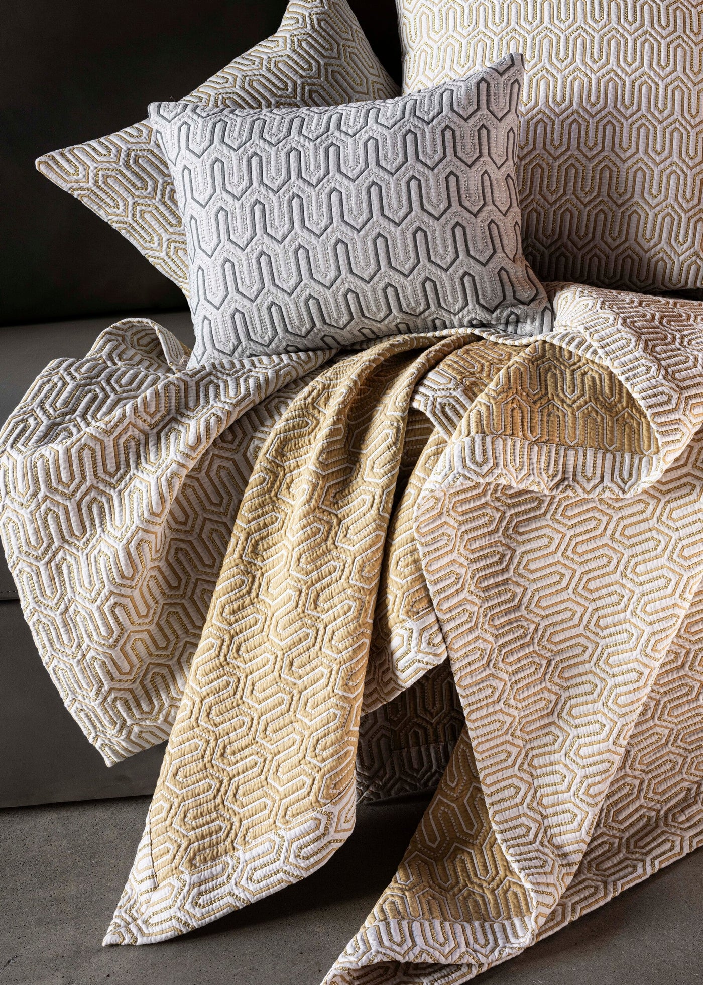 Close-up of Celso de Lemos Vendome pillow covers in grey and gold geometric pattern on chair.