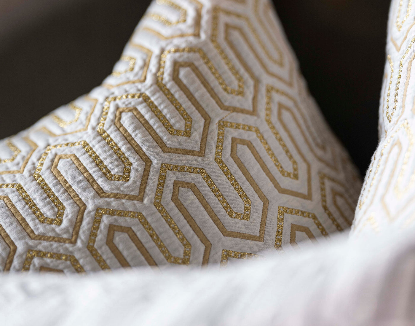 Close-up of gold geometric embroidery on ivory Vendome pillow cover corner detail.