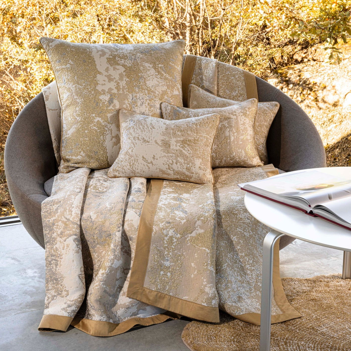 Decorative pillows and blanket on a chair with a blurred natural background
