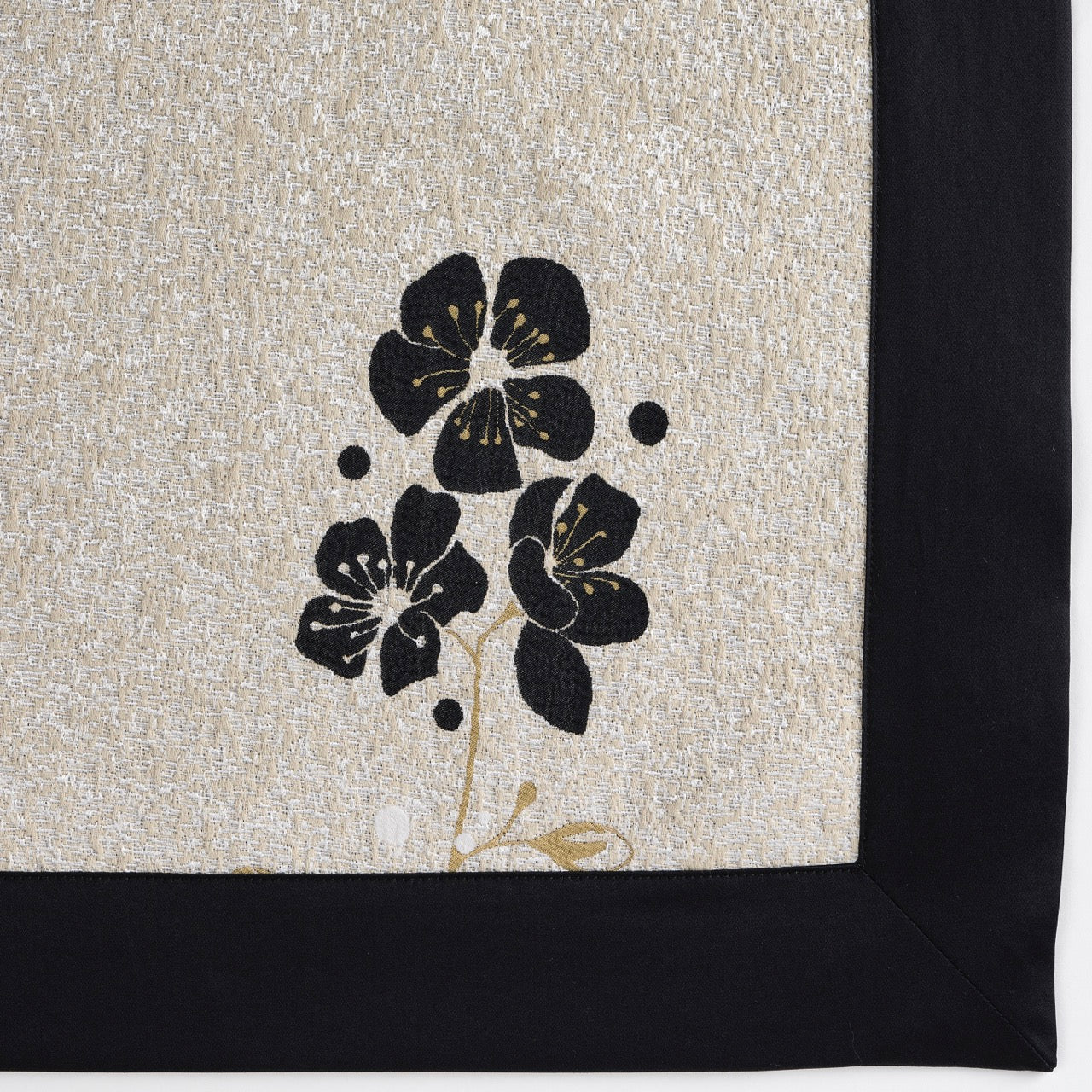 Close-up of black floral embroidery and contrast border on champagne linen euro sham.