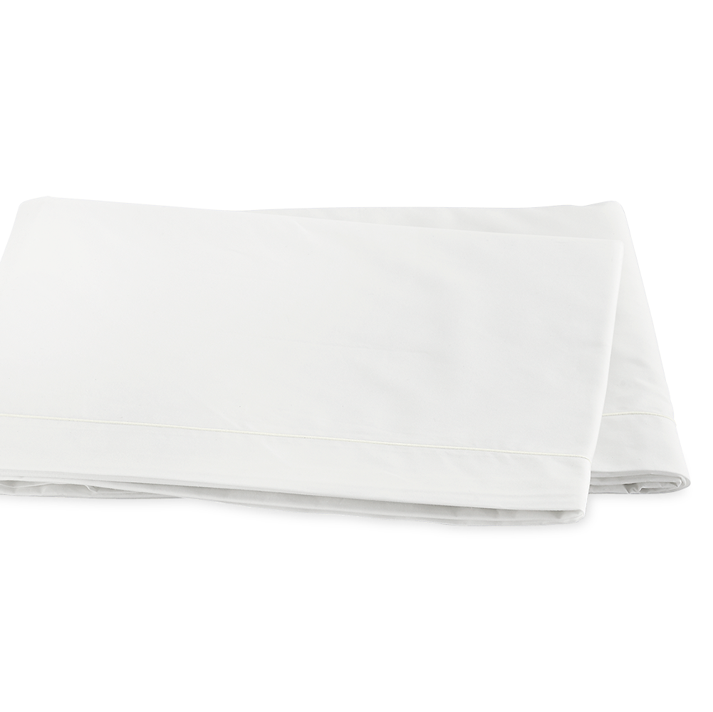 Matouk Ceylon flat sheet in white cotton with satin stitch border, neatly folded.