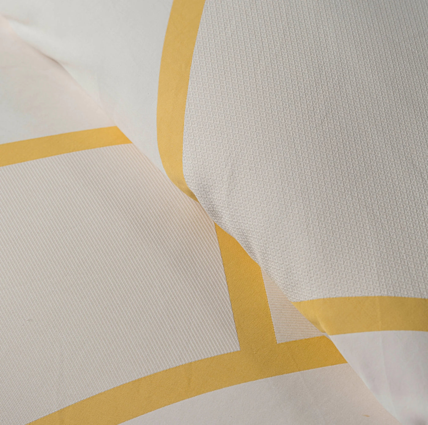 Close-up of ivory woven cotton pillowcase with buttercup yellow border detail.