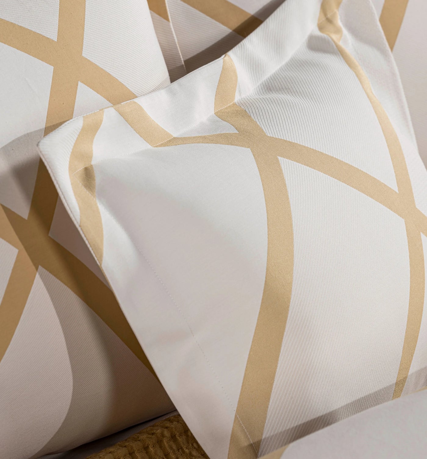 Close-up of Celso de Lemos Charleston pillowcase showing champagne geometric stripe pattern on ivory cotton.
