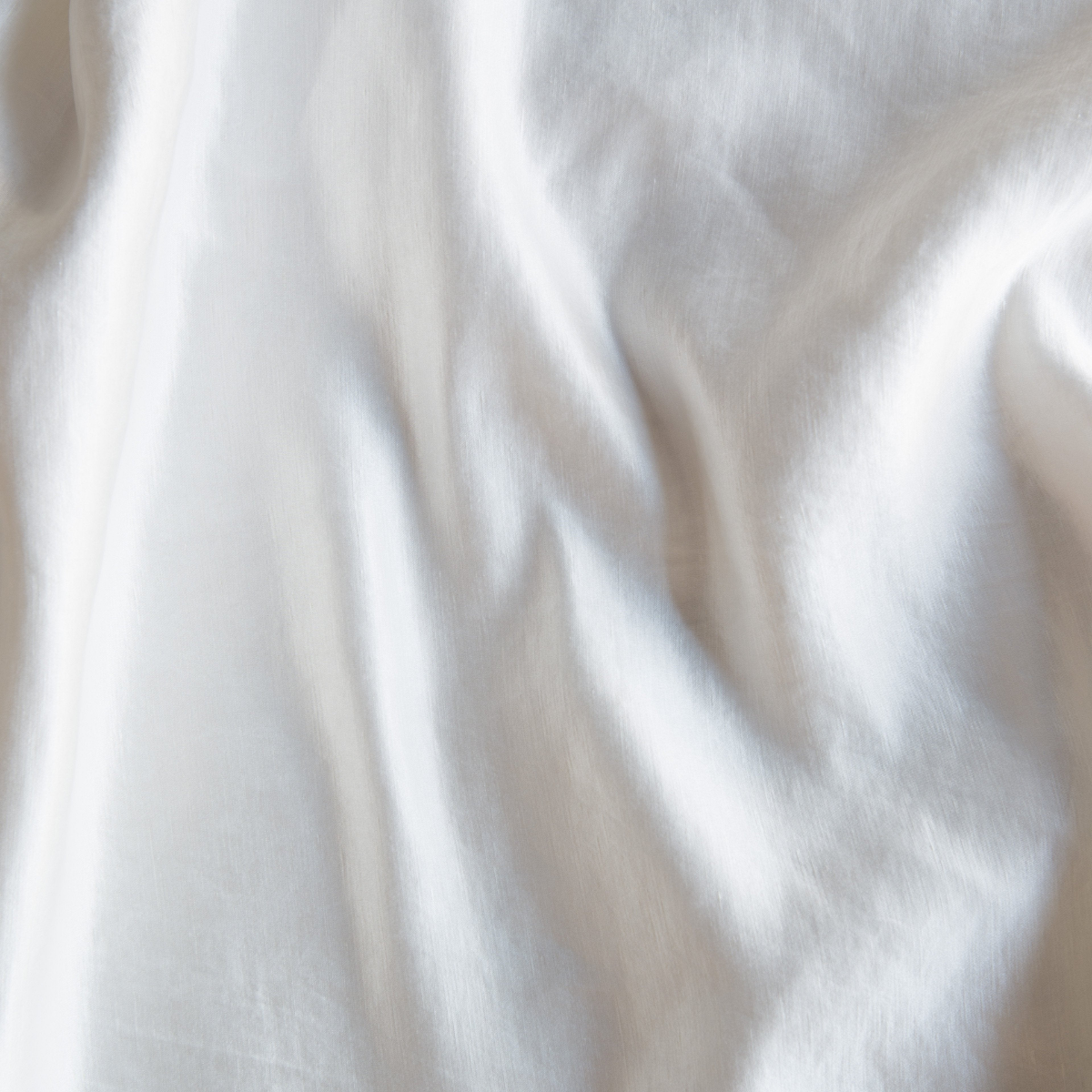 Close-up of Winter White Bella Notte Paloma pillowcase fabric with soft, draped folds.