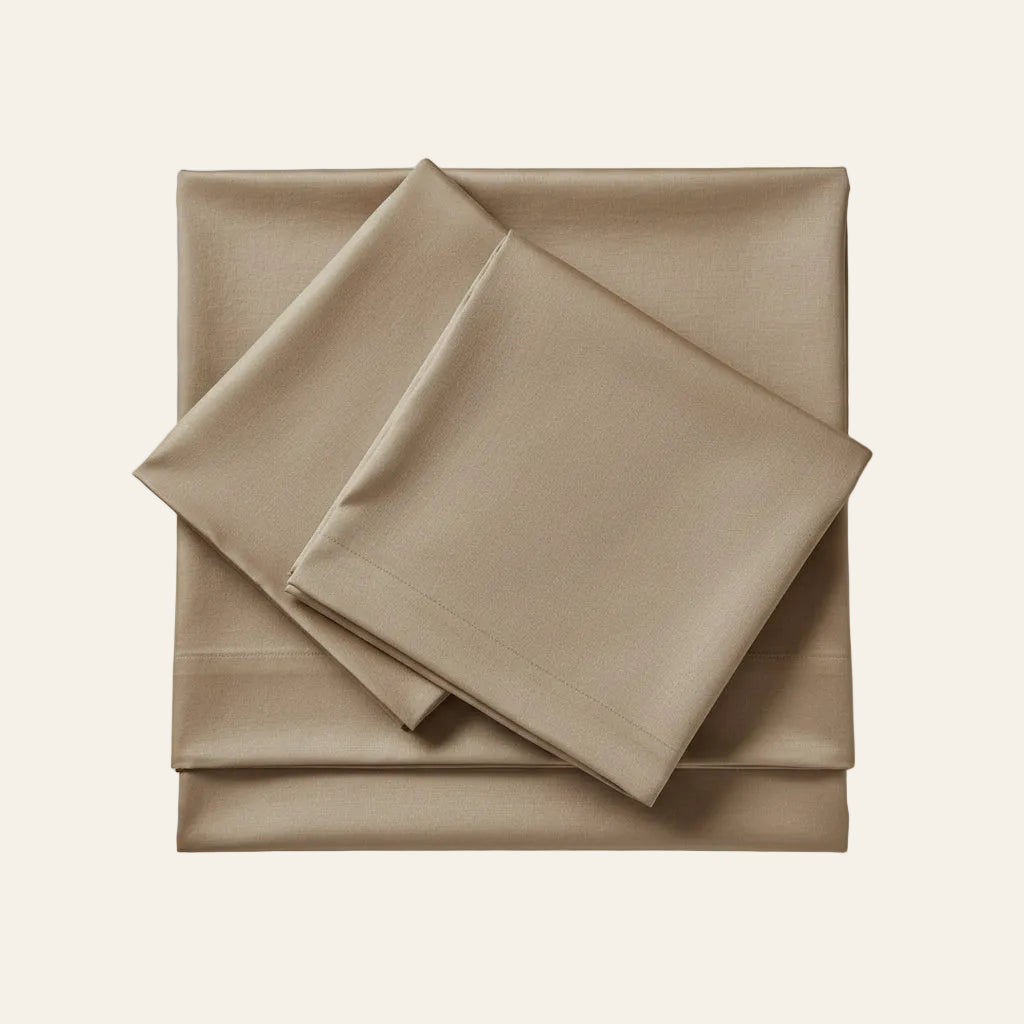 Ann Gish Charmeuse sheet set in taupe, neatly folded and stacked on neutral background.