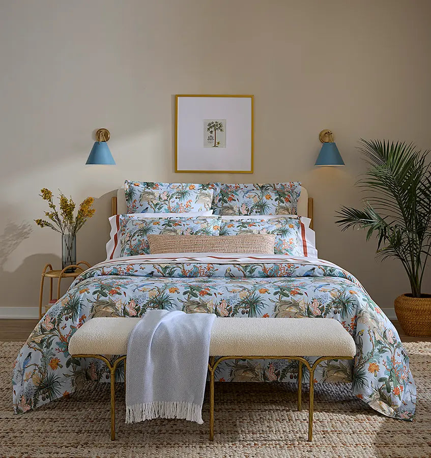Close-up of Sferra Cinque Terra duvet cover in soft blue tropical botanical print on styled bed.