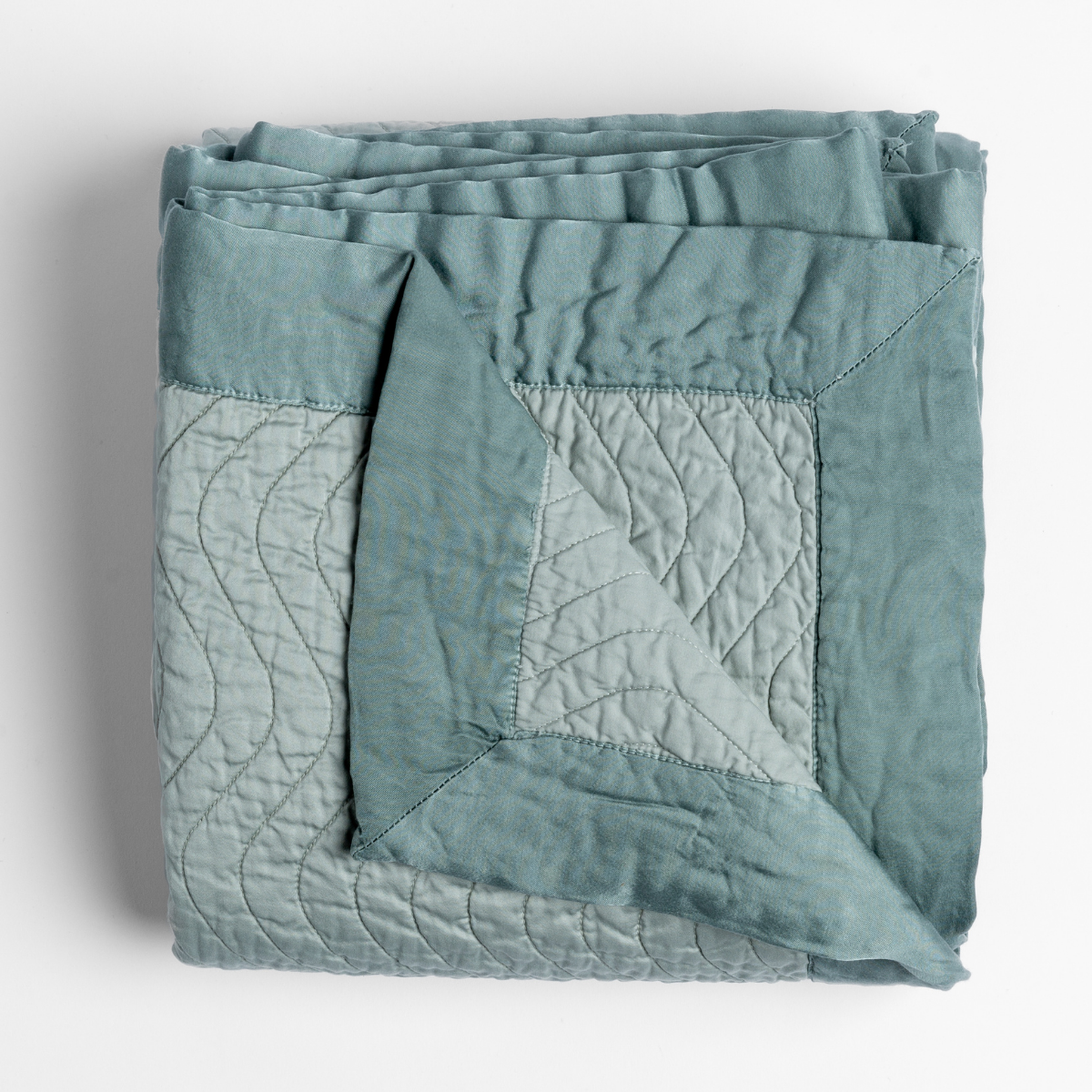 Folded Eucalyptus Cirillo throw showing quilted leaf stitching and contrast reverse panel.