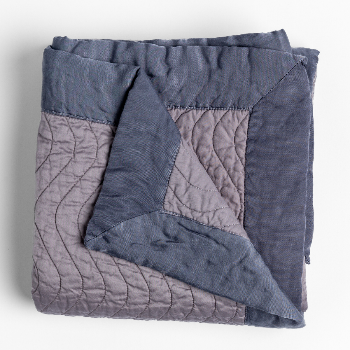 Folded Bella Notte Cirillo blanket in French Lavender, showing quilted wave stitching and two-tone reverse.