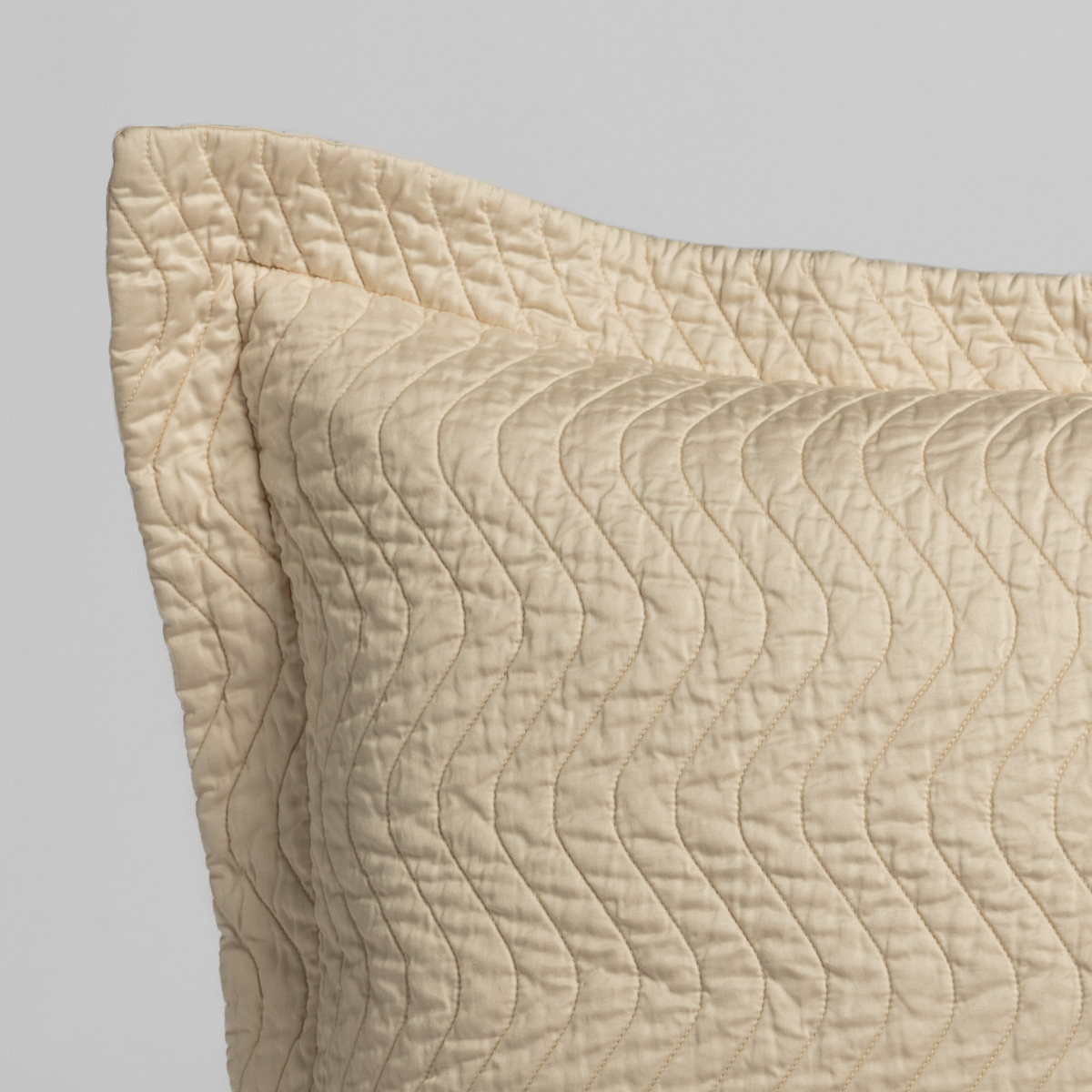 Close-up of Natural quilted sham corner showing wave-pattern stitching and flange edge detail.