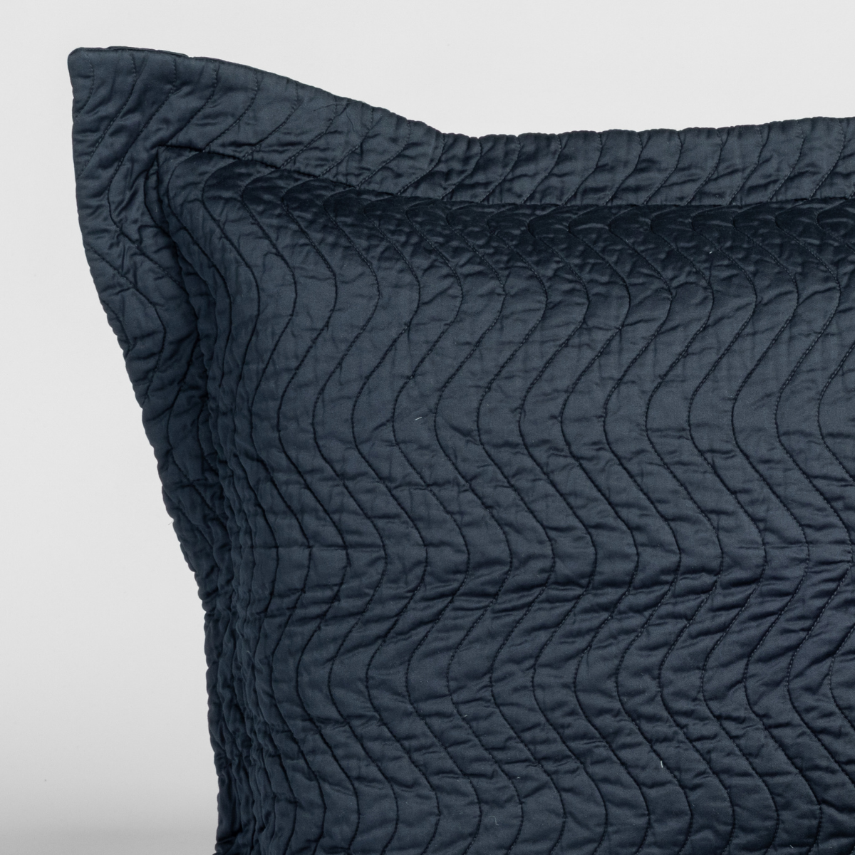 Close-up of Slate quilted pillow sham corner showing wave-stitched texture and flanged edge.