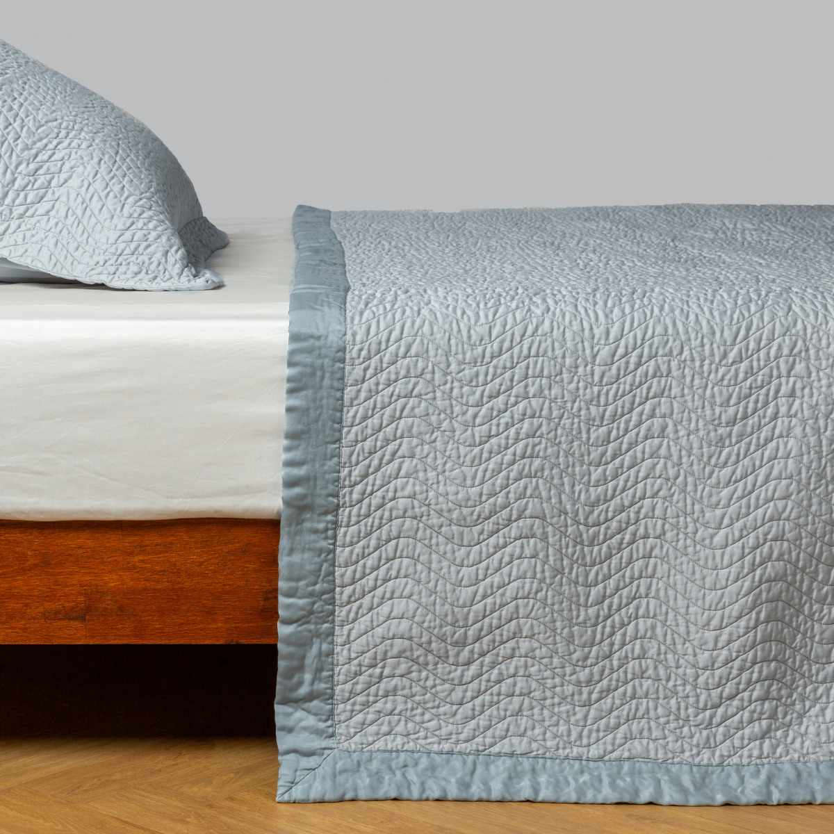 Bella Notte Cirillo coverlet in Cloud draped over bed foot, showing quilted texture and border trim.