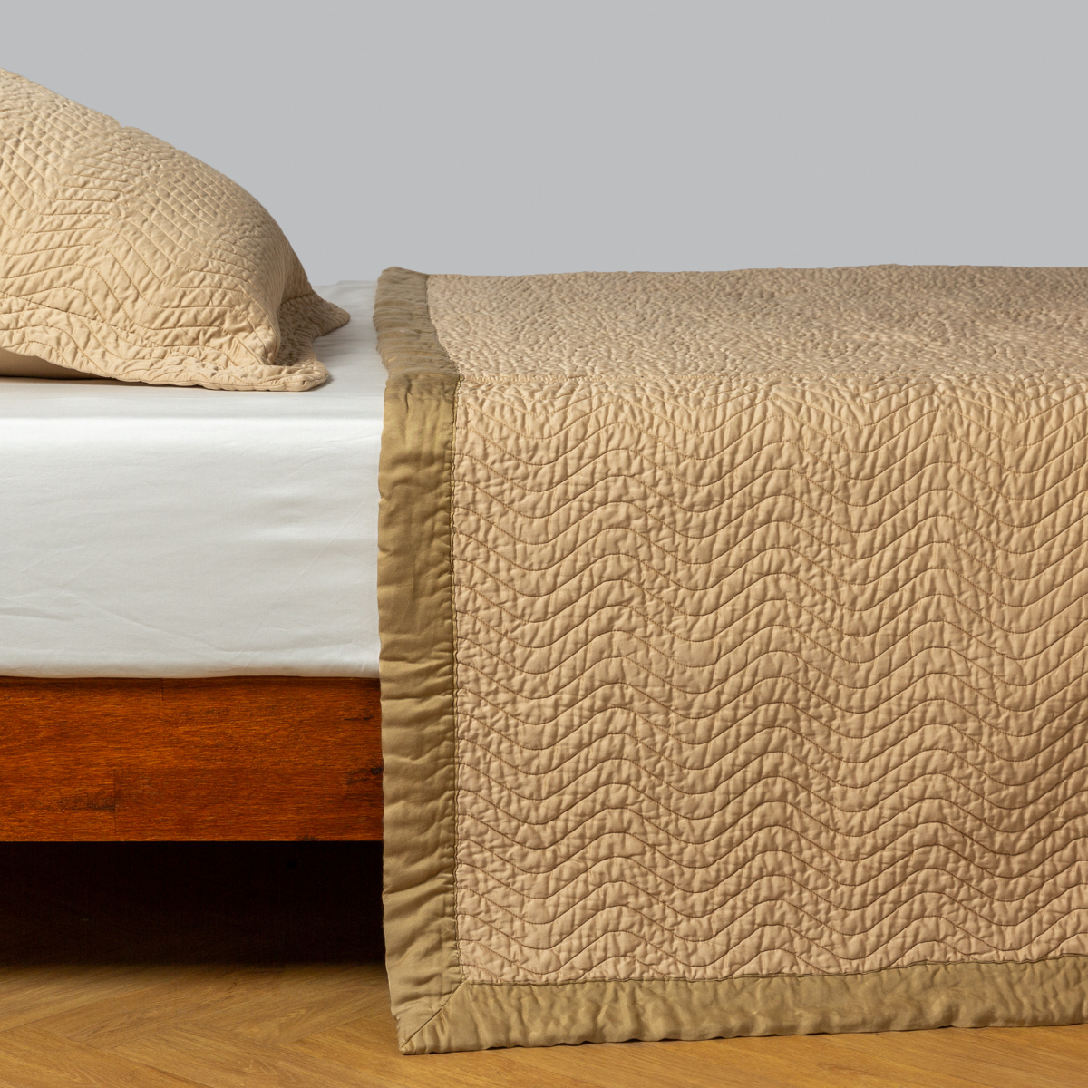 Bella Notte Cirillo coverlet in Honeycomb draped over bed corner, showing quilted wave texture and border detail.