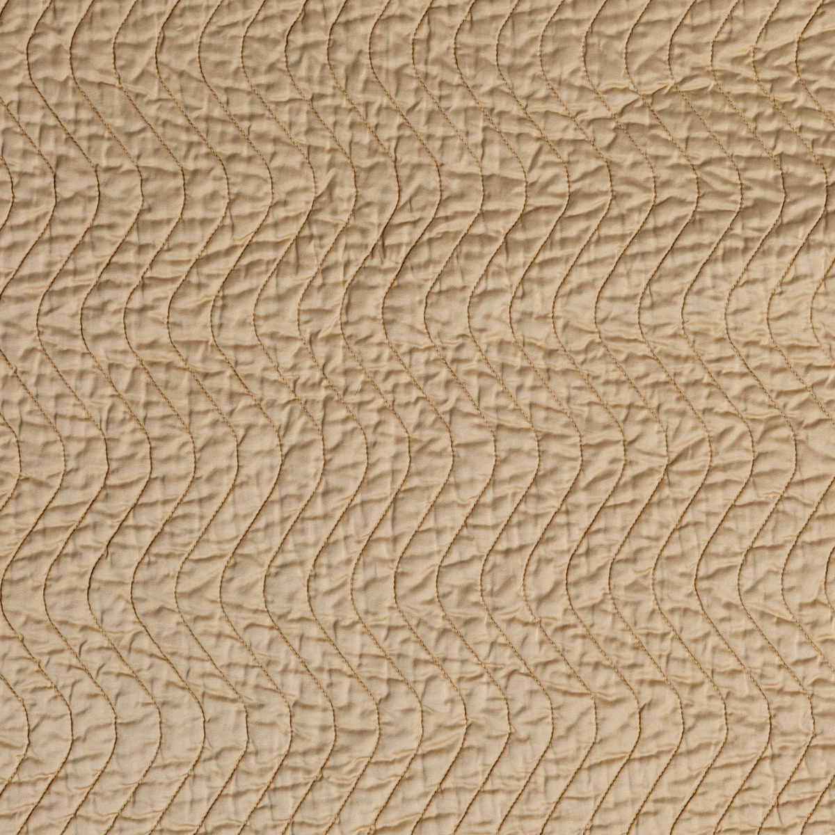 Close-up of Honeycomb Cirillo coverlet's quilted wave stitch pattern in warm golden fabric.