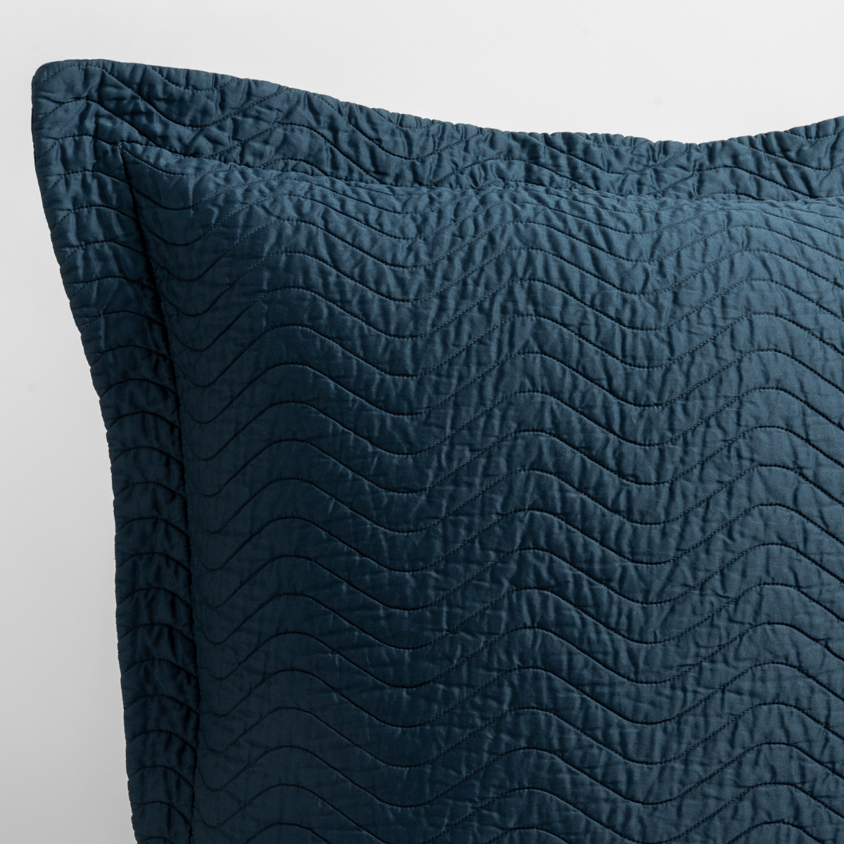 Close-up of Midnight quilted pillow corner showing wave-stitched texture and knife-edge trim.