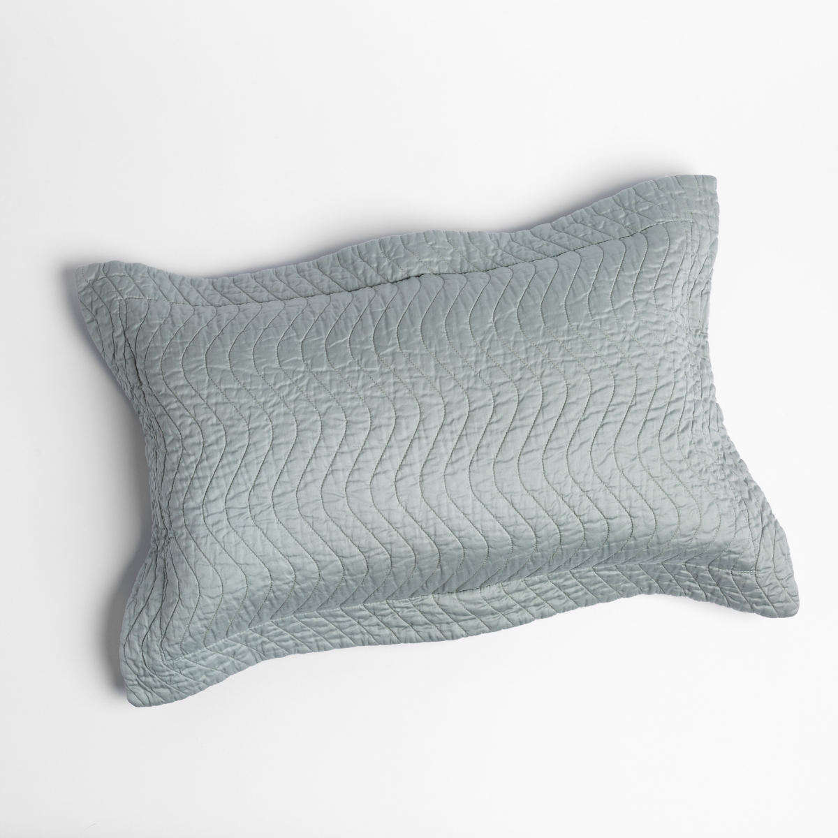 Eucalyptus quilted throw pillow with wave-pattern stitching and scalloped flange edge.