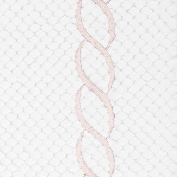 Close-up of blush chain embroidery border on white tufted cotton bath rug.