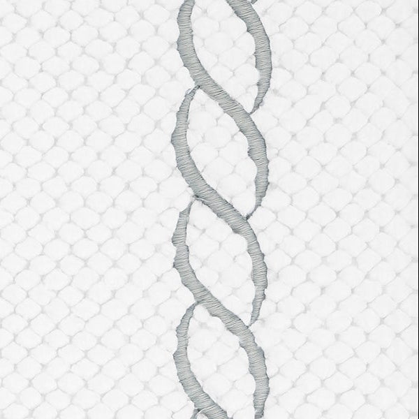 Close-up of silver chain embroidery detail on white waffle-textured cotton bath rug.