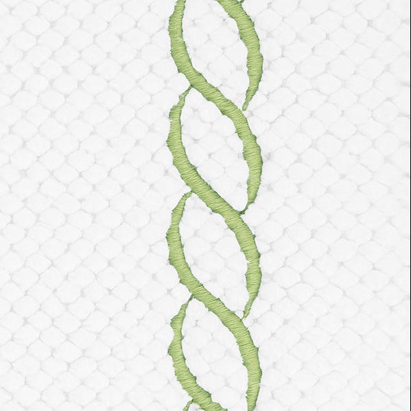 Close-up of sage green chain embroidery on white textured cotton bath rug.