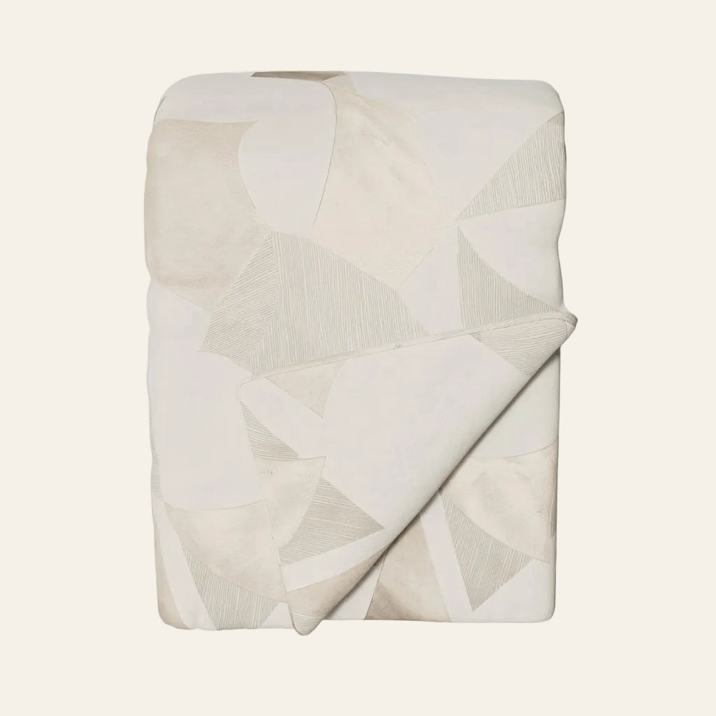 Ann Gish Clio throw in ivory with geometric patchwork pattern, neatly folded.