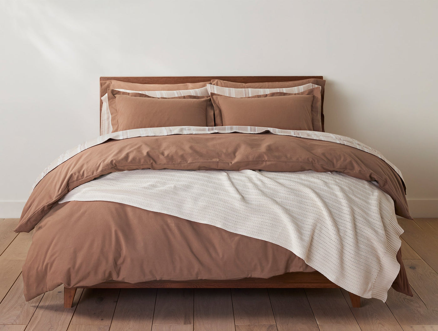 Coyuchi Casa Loma Knit Throw draped over terracotta bedding in styled bedroom scene.