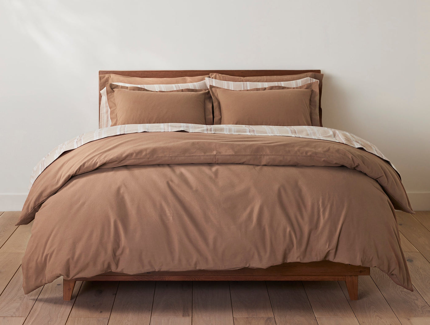 Coyuchi Cloud Brushed Flannel sheet set in caramel, styled on a wood-frame bed.