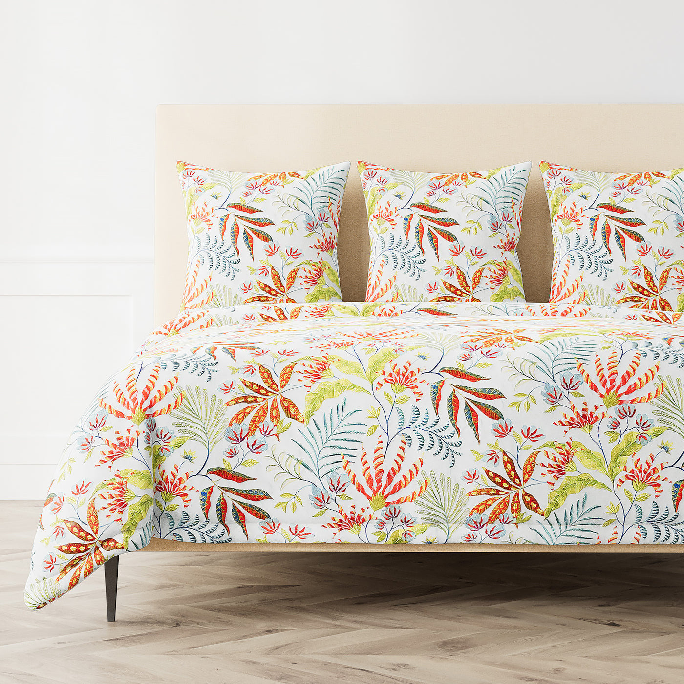 Tropical botanical print duvet in orange, red, and green on white, styled on a bed.