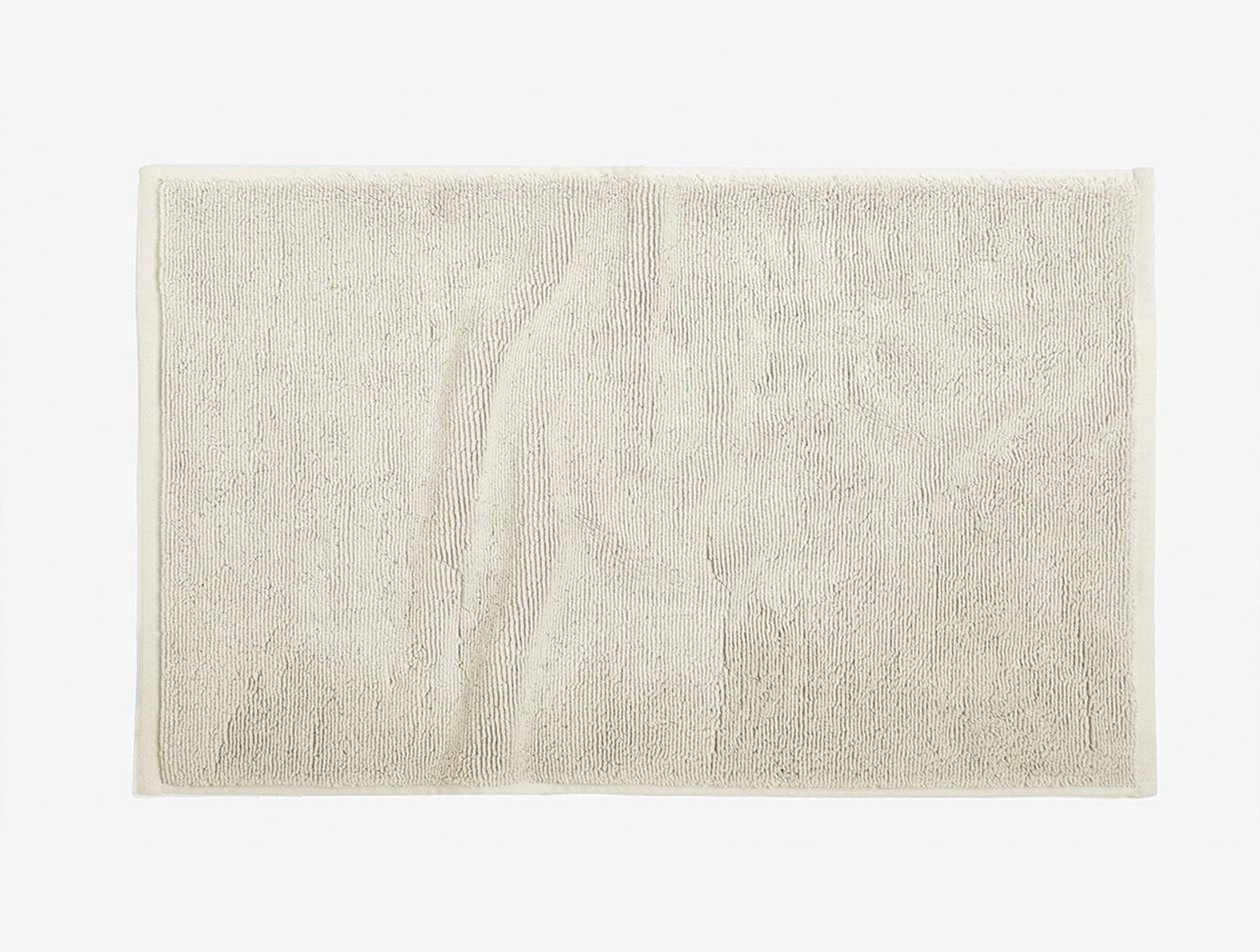 Close-up of Coyuchi Cloud Loom bath rug in ivory, showing plush terry texture and flat border trim.